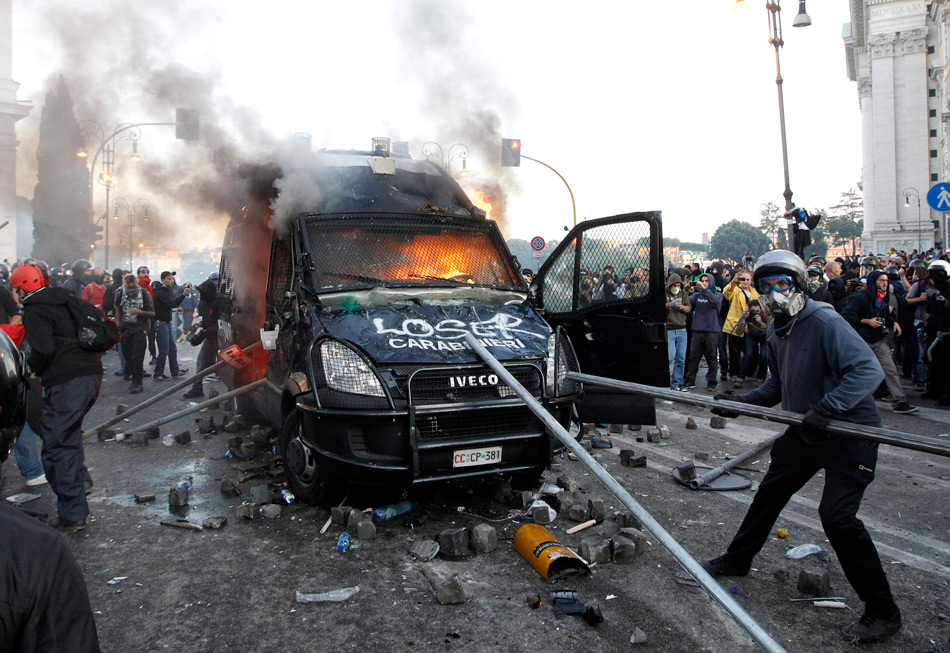 Демонстранты разбивают полицейскую машину во время всемирной акции протеста. 15 октября 2011. Рим, Италия 