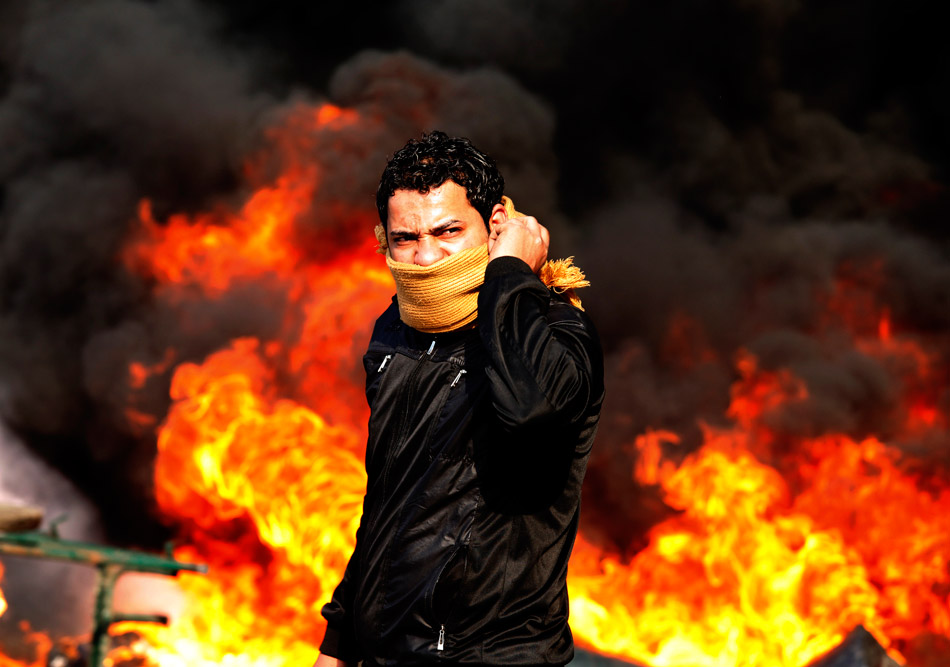 Каир (Египет). Демонстрант у горящей баррикады. Полиция четвертый день не может справиться с беспрецедентными массовыми выступлениями на улицах Каира. Участники демонстраций добиваются свержения президента Хосни Мубарака, правившего Египтом тридцать лет. 28 января 2011 года