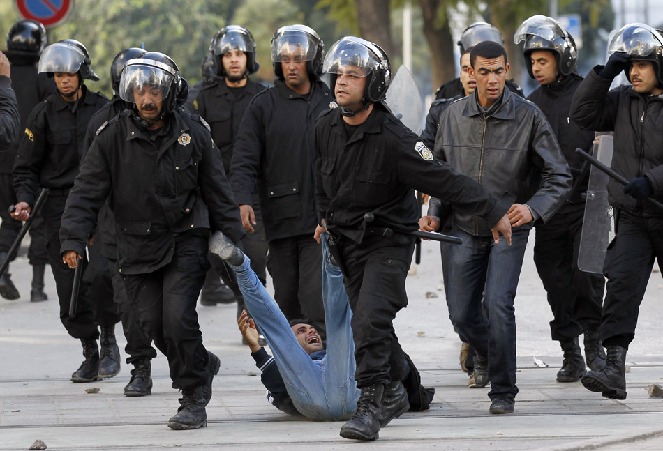 Тунис (Тунис). Полицейские из спецподразделения по борьбе с уличными беспорядками задерживают демонстранта. 14 января 2011 года