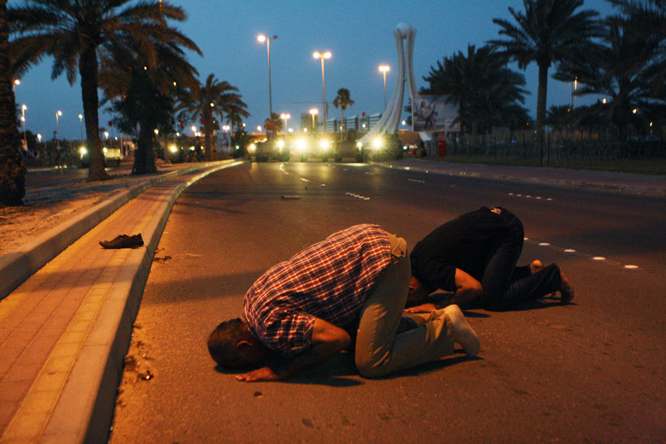 Манама (Бахрейн). Участники антиправительственных демонстраций молятся в разгар столкновений со спецподразделениями армии Бахрейна неподалеку от Жемчужного перекрестка в столице страны Манаме. 18 февраля 2011 года