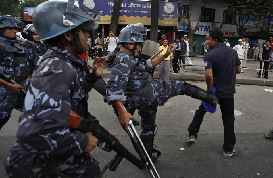 Катманду (Непал). Полицейский пинает демонстранта из промонархической  Национально-демократической партии Непала, который прорвался сквозь ограждение у здания Конституционного собрания Непала. 25 мая 2011 года