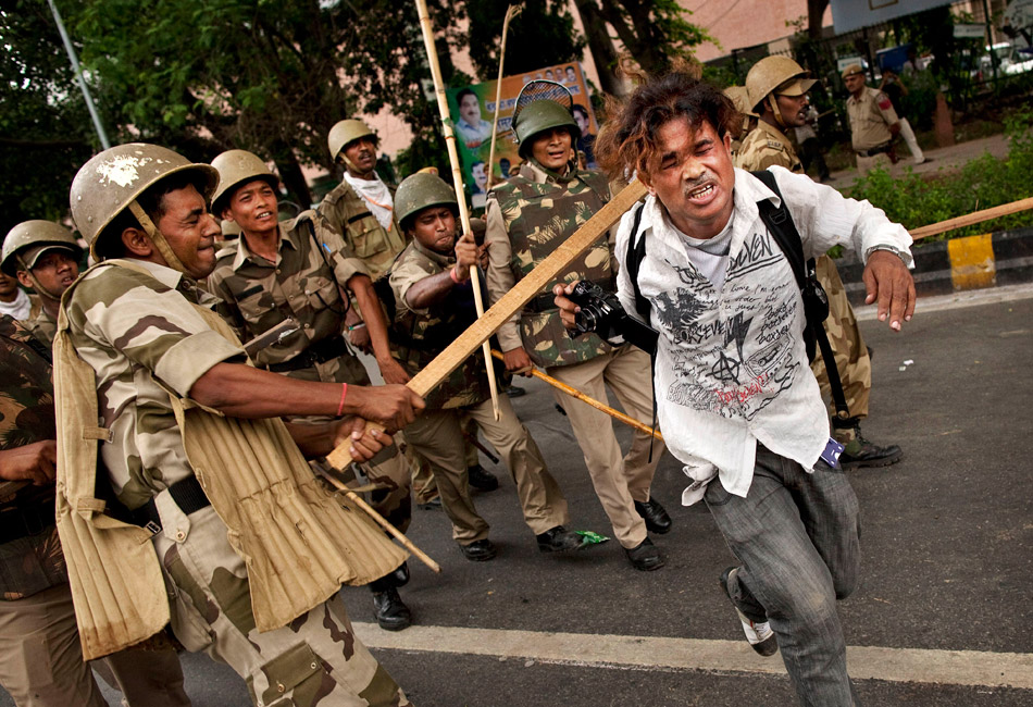 Нью-Дели (Индия). Полицейский бьет фотокорреспондента Шакхара Гоша из газеты Dainik Bhaskar во время антикоррупционной демонстрации сторонников оппозиционной партии BJP у обсерватории Джантар-Мантар в Нью-Дели. 9 августа 2011 года