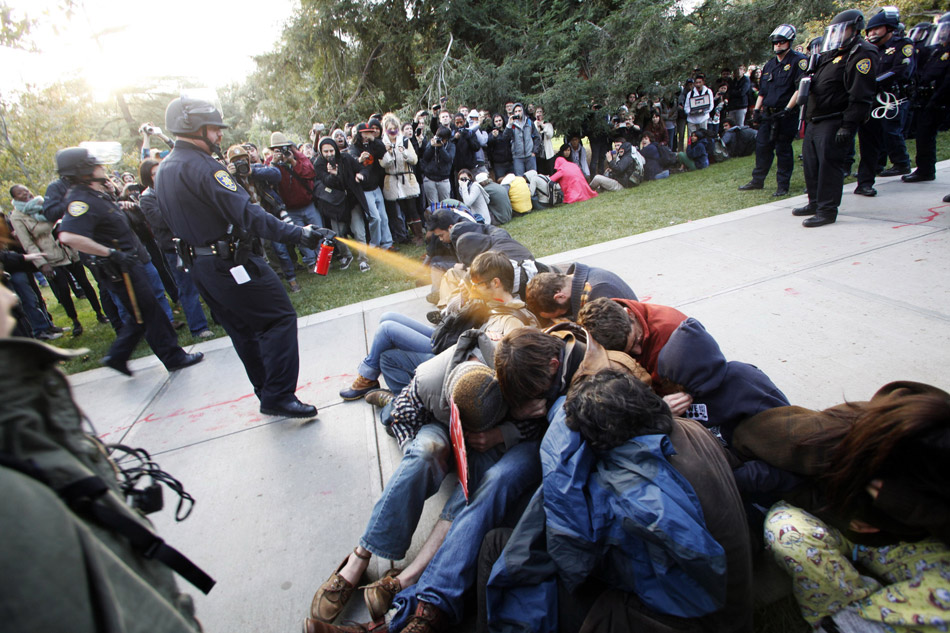 Калифорния (США). Лейтенант полиции Джон Пайк применяет перечный газ против демонстрантов из движения «Захвати Калифорнийский университет в Дэвисе». 18 ноября 2011 года