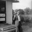 Неизвестный автор. Средний план мужчины, стоящего перед задним входом дома и целящегося из пистолета себе в голову. 1942 