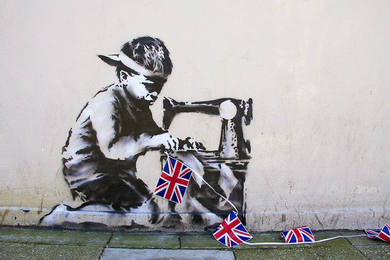 На Бриллиантовый юбилей королевы, который празднуется в этом году, художник и политический активист Бэнкси оставил на лондонской улице изображение азиатского мальчика, шьющего британские флажки.